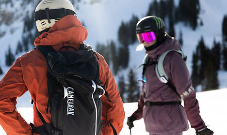 Two skiers on a mountain wearing snow packs.