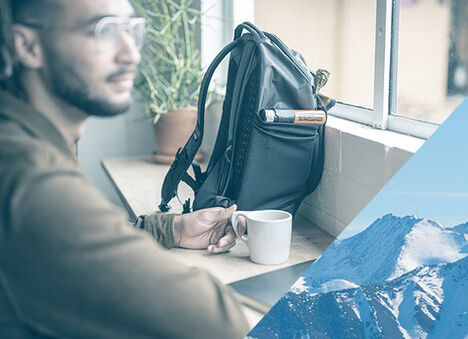 Man working from a coffee shop with a M.U.L.E. commute pack.