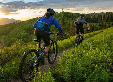 Two bikers with M.U.L.E Waist Packs on while going down a trail