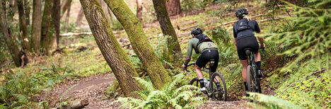 Two bikers confidently going down a trail.