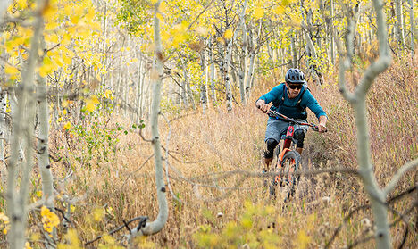 Mountain biker riding through a trail with a hydration vest on.