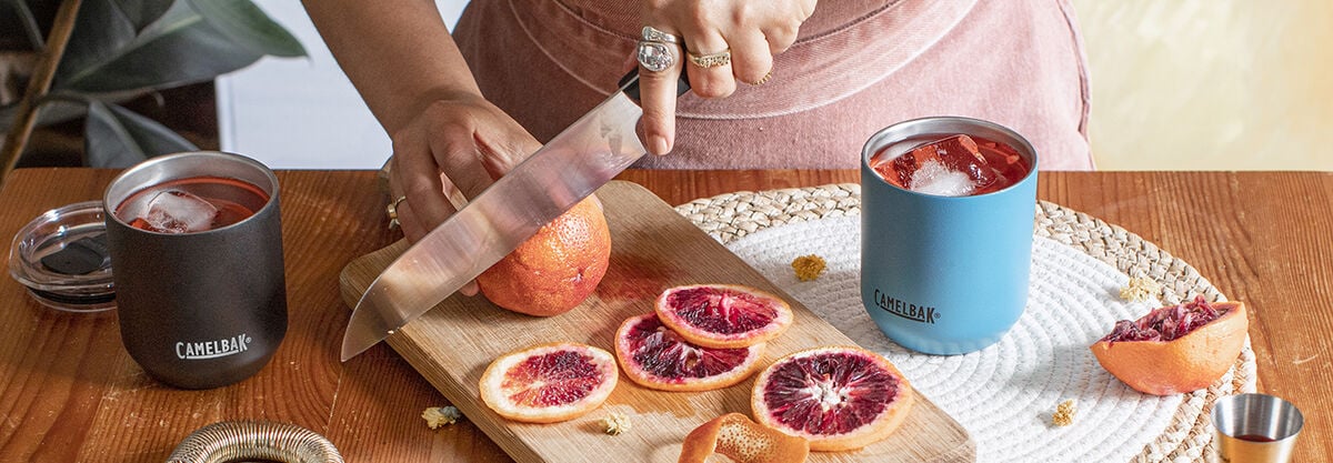 Two cocktail glasses with blood orange slices on a cutting board. 