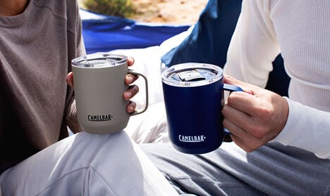 Two mugs being held outside.