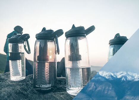 Four Eddy+ LifeStraw bottles lined up with the sun glowing through them.
