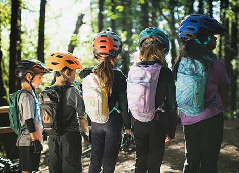 Five kids standing with different Mini M.U.L.E. hydration packs on.