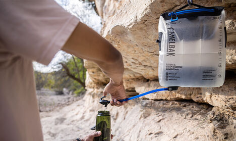 A person filling a Tritan Renew water bottle from a Camelbak Group Reservoir.