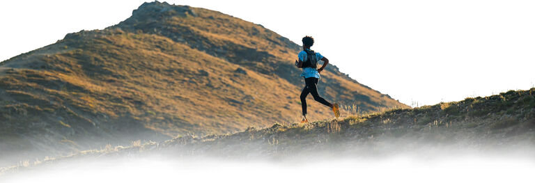 Man running on a trail on a hill.