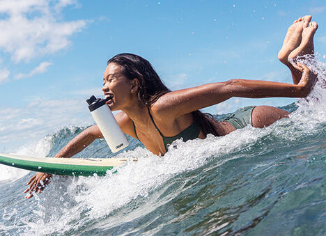 Surfer holding a white Chute Mag in her mouth.