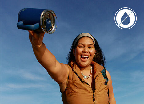 Girl smiling while holding a Thrive mug on it's side, showing it's leak-proof capabilities.
