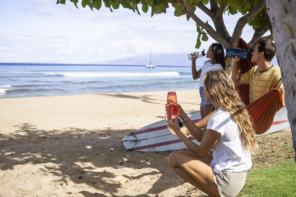 People on a beach sipping from water bottles.