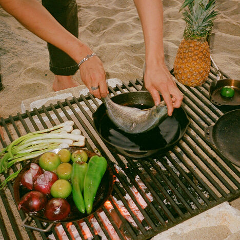 Brian cooking fresh fish with a cast iron over an open flame.