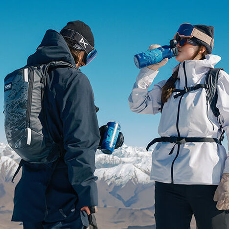 Two skiers stopping to take a sip from their CamelBak x POW LE collection