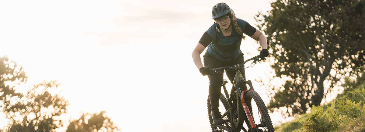 Women on mountain bike wearing a helmet, protective eye glasses and a CamelBak pack.