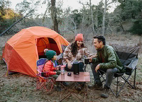 Image of a woman, man, and child outside of a tent. Image of a woman, man, and child outside of a tent.