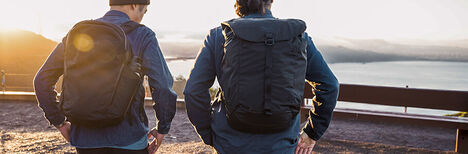 Two guys with ATP backpacks on, overlooking a bay