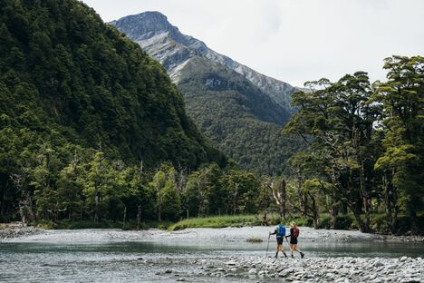 2 hikers wearing Rim Runner packs hiking through a river valley in the mountains 2 hikers wearing Rim Runner packs hiking through a river valley in the mountains