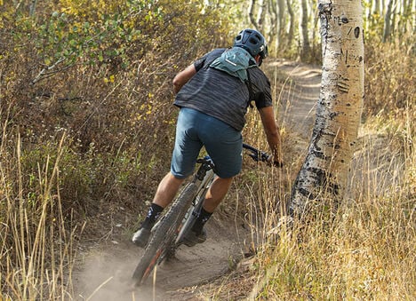 Mountain biker riding on a trail wearing a hydration backpack..