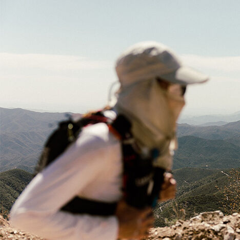 Sally looking ahead at a trail to the right while mountains are off in the distance.