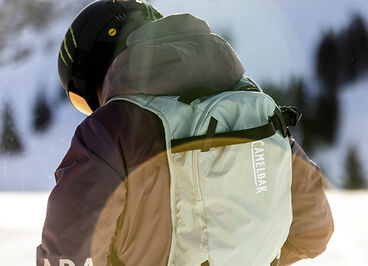 Woman gearing up on the mountain with her snow pack on.