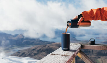 Person putting water from a river in their CamelBak filtered by LifeStraw water bottle. 