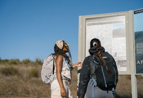 Two hikers stopping at a trailhead before starting their adventure.