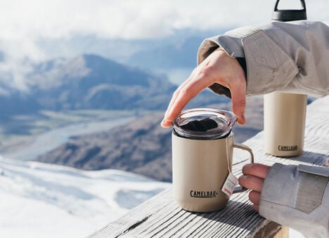 Snowy Mountain background with a Camp Mug sitting on a railing and multibev behind it. Snowy Mountain background with a Camp Mug sitting on a railing and multibev behind it.