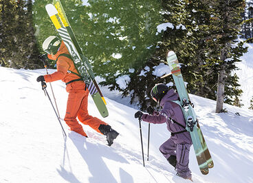 People walking up a mountain with their skis on their CamelBak hydration packs.