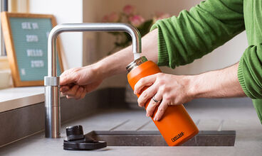 Man in plaid shirt cleaning water bottle.