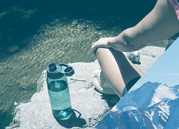 Person sitting by a lake enjoying the view with a Chute Mag bottle next to them.