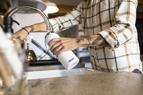 Image of man refilling a reusable stainless steel water bottle.