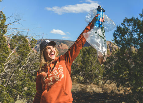 Woman holding up Earth Day Water Bottle and Clean Up Kit. Woman holding up Earth Day Water Bottle and Clean Up Kit.