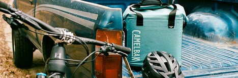 A ChillBak Cube 18 on the back of a truck bed with a bike helmet in front of it.