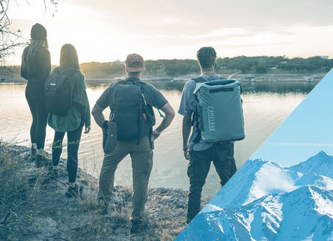 Four friends standing near the edge of a lake and one is wearing a ChillBak soft cooler.