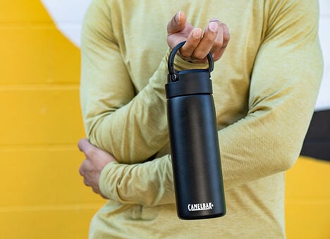 Guy holding a water bottle against a yellow background.