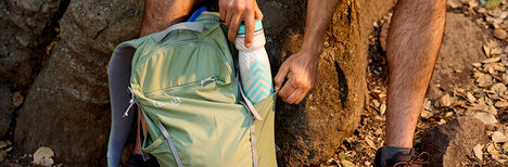 Person putting a Podium water bottle inside of a Hiking Hydration Pack
