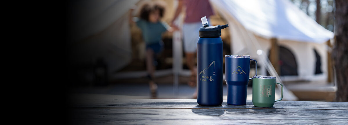 Three customized bottles on a picnic table with campers in the background