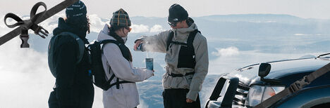 Three skiers on top of a mountain with new POW Limited Edition gear on.