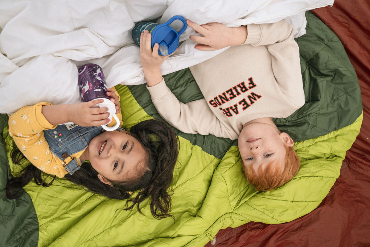 Two kids laying on sleeping bags. Two kids laying on sleeping bags.