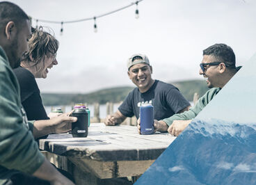 A group of friends enjoying a drink out of can coolers.