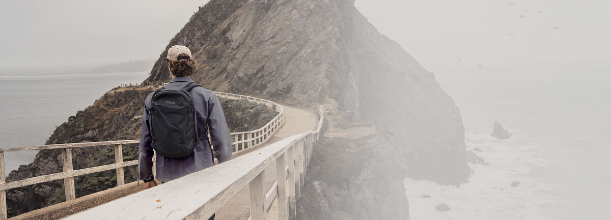 Man walking on a bridge with the ATP 20 backpack on.