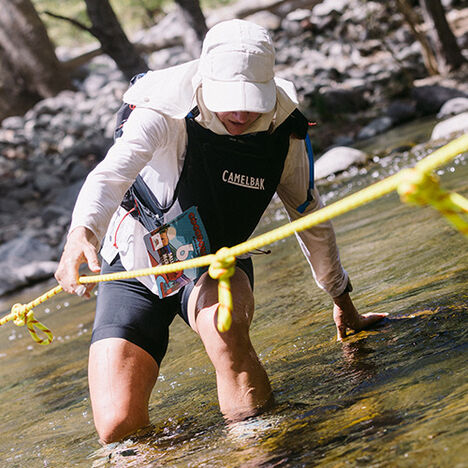 Sally using a guide rope to make her way across a creek.