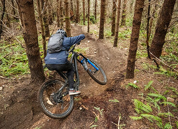 Mountain biker riding down a trail with a hydration pack on.
