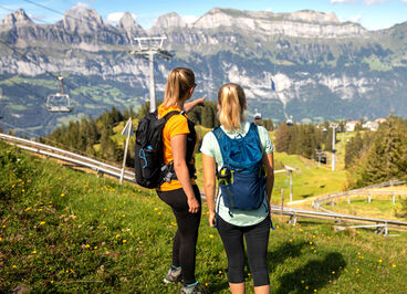 Two women wearing hydration backpacks.