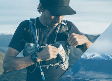 Man taking a snack bar out of the front pocket of his Zephyr vest.