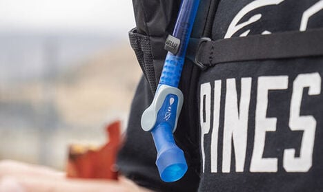 A bite valve hanging from a hydration pack.