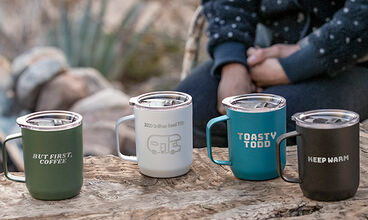 Four camp mugs with different designs engraved on each.