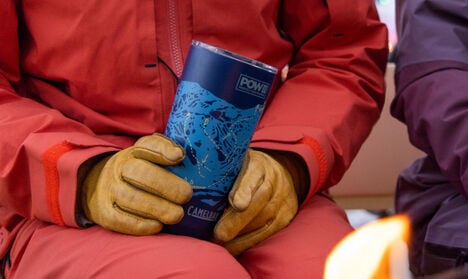 A skier bundled up in warm clothing while holding a 20oz POW Limited Edition Tumbler