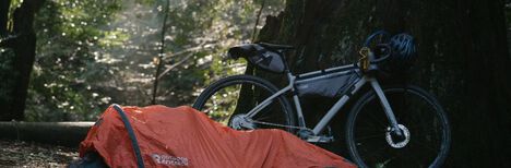 A bike with M.U.L.E. on-bike packs set up at a camp site.