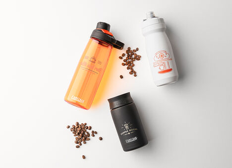 Three customized bottles with coffee beans on white background.