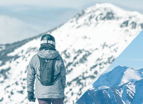Person looking at a snowy mountain in the distance while wearing a snow hydration pack.